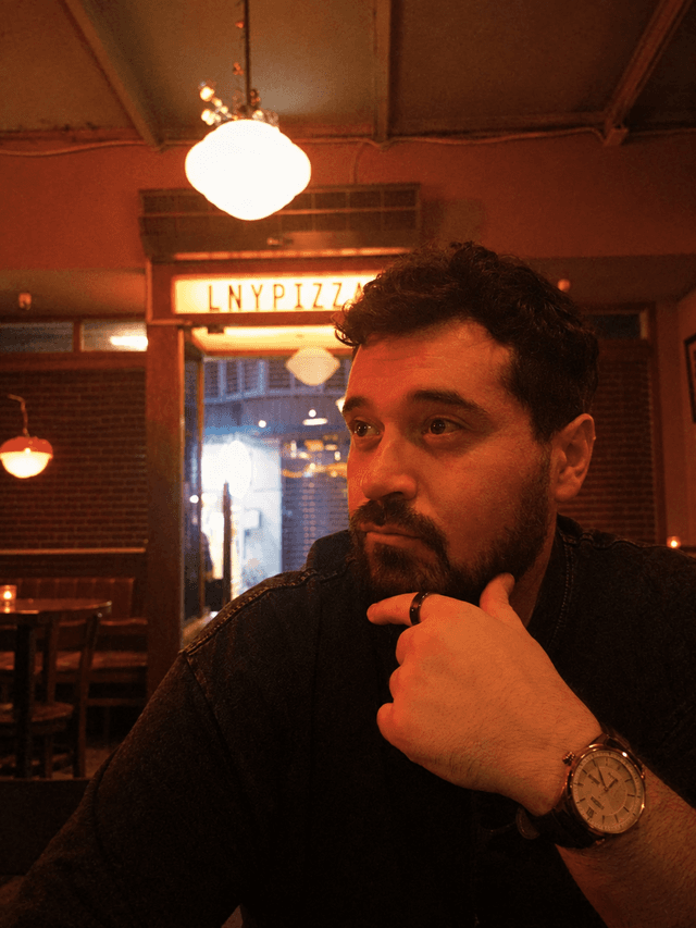Michael D Whitt in a dimly lit pizza restaurant staring off into the distance